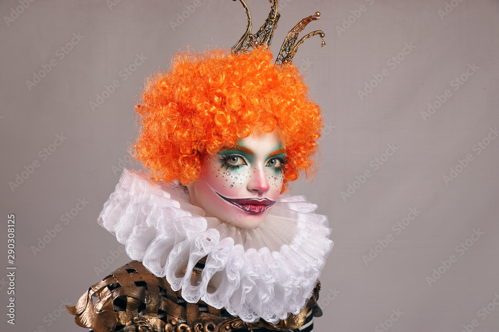 Red sad clown . Beautiful girl with bright clown makeup with red wig and smile. frame, gray background . Stock Photo | Adobe Stock