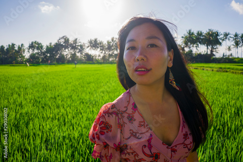 outdoors lifestyle portrait of young beautiful and happy Asian Korean woman enjoying walk at green rice field under blue sky on a Summer sunny day feeling carefree