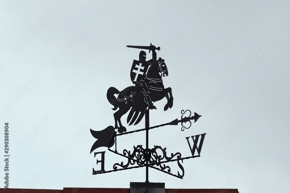 Weathervane in the form of a crusader with a horse with a sword in his hand. A product made of metal on the roof of the house. Weathervane in the form of a crusader with a horse with a sword in his hand. A product made of metal on the roof of the house.