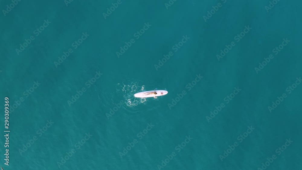 Ragazza con costume arancione va sulla tavola da surf in mare. Vista aerea con drone. Ragazza con costume arancione va sulla tavola da surf in mare. Vista aerea con drone.