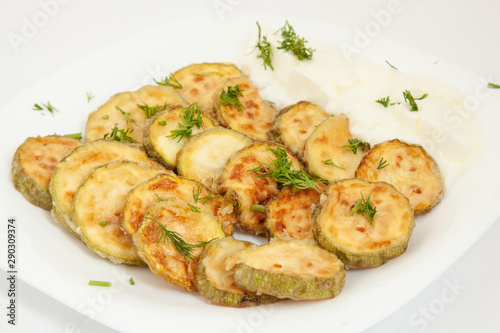 Fried zucchini with yogurt in white plate.