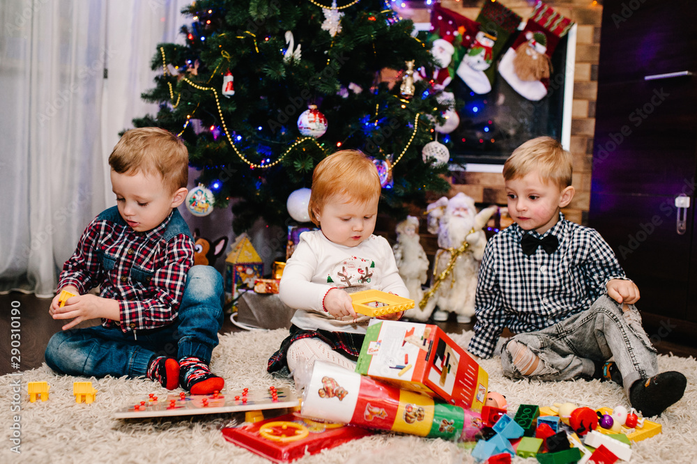 Happy family: children, kids, daughter and son, boy and girl unpack gifts near the Christmas tree and fireplace. New year concept. Merry Christmas. Happy family: children, kids, daughter and son, boy and girl unpack gifts near the Christmas tree and fireplace. New year concept. Merry Christmas.