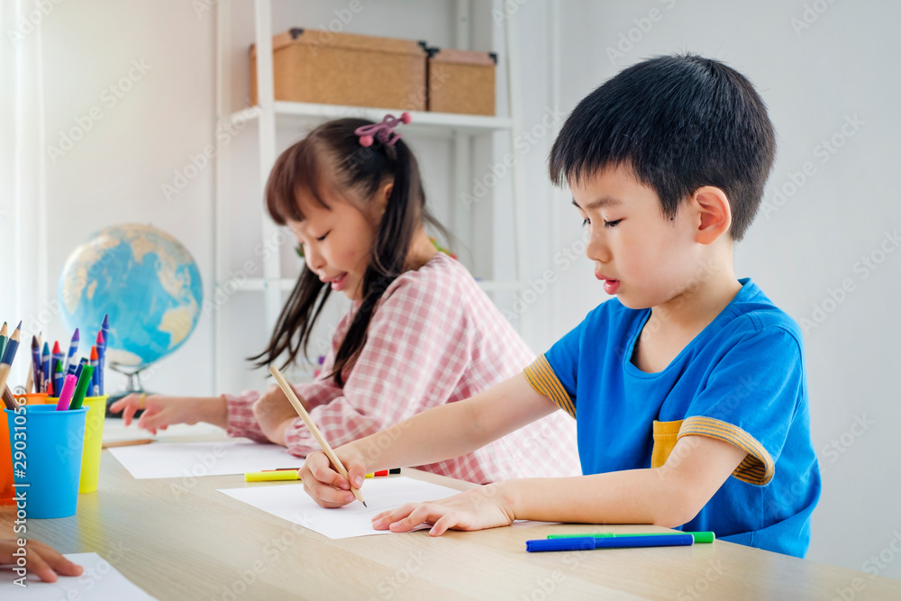Children drawing picture with pencils in classroom Children drawing picture with pencils in classroom
