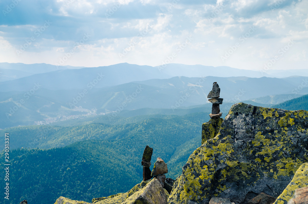 Huge stones covered with green lichen lie on the top of the mountain against the backdrop of ancient, high mountain ranges Huge stones covered with green lichen lie on the top of the mountain against the backdrop of ancient, high mountain ranges