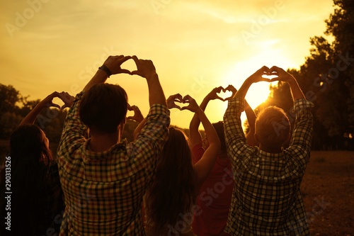 Hands in the shape of hearts on a sunset