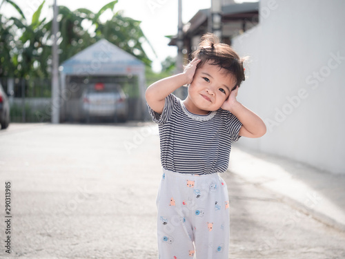 Portrait of asian cute little girl standing on the street in the morning. Natural sunlight