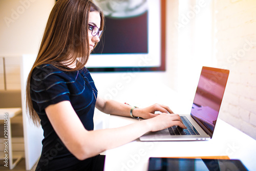 Woman distance content manager publishing information in web site via laptop computer, sitting in coworking space. Female administrator groups in social network keyboarding article via notebook