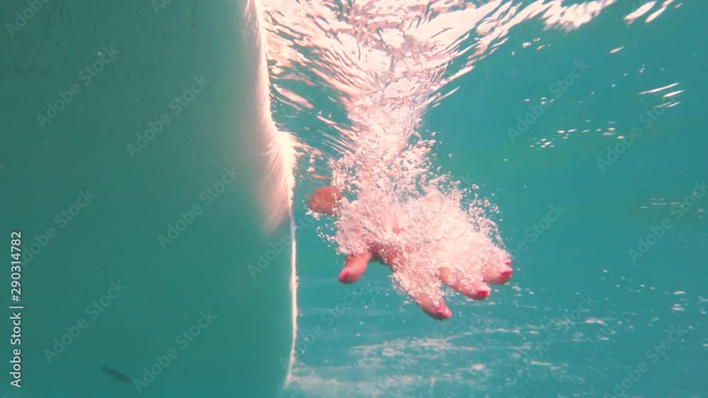 Mano sott'acqua di una ragazza sulla tavola da surf in mare