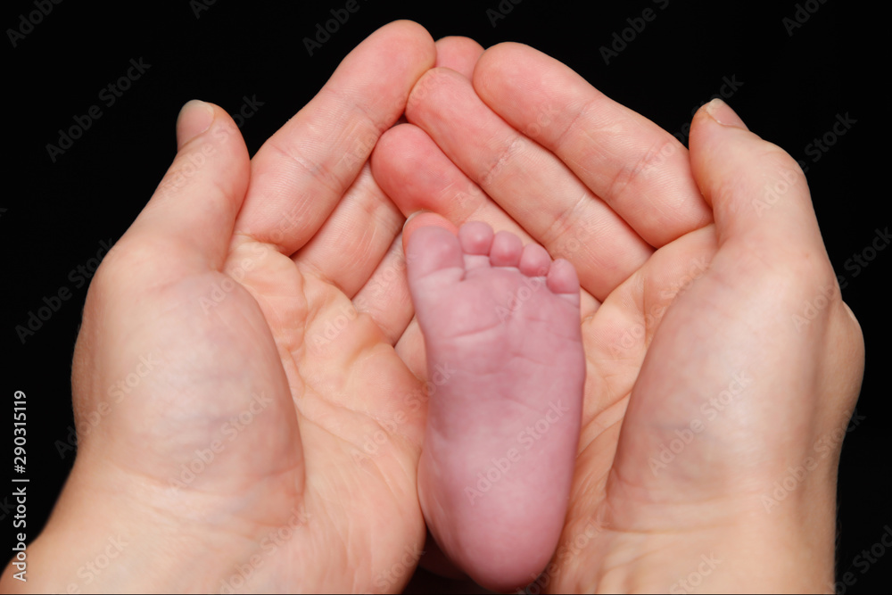Newborn baby's feet in father's hand