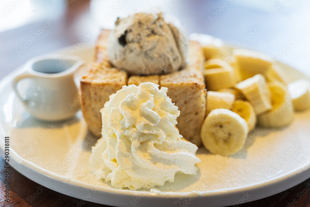 Close Up on, Honey Toast, Bread Buttered Toast, Banana, Ice Cream and Whipped Cream Dessert on a white Dish