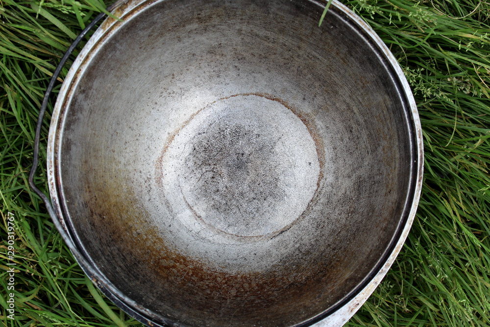 an empty cooking pot on the street stands on the lawn in the grass an empty cooking pot on the street stands on the lawn in the grass