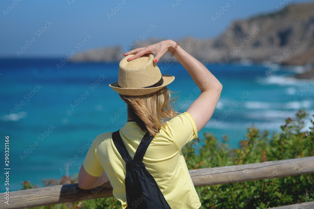 Stylish Woman is standing on cozy nature balcony with sea view. She is spending her summer vacations broad travelling and enjoying different views.