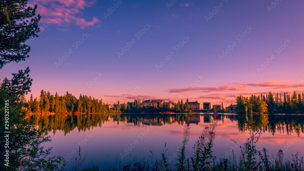 Sunset over Strbske pleso - tarn in High Tatras national park, Slovakia. There are trees and chalet reflections in the lake
