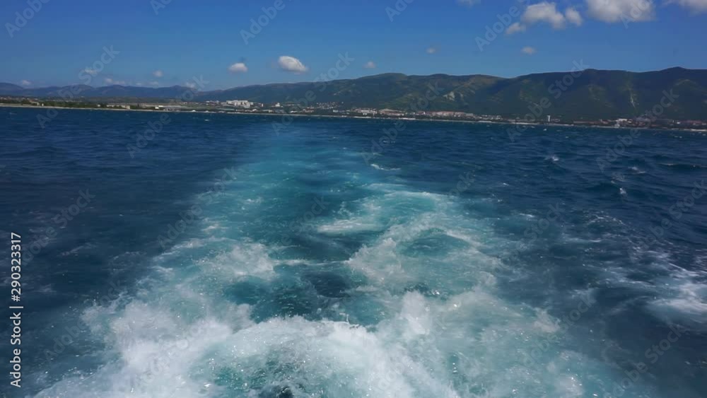 A water trail is formed using a boat. A water trail foams behind a boat sailing on the sea.Sea landscape with mountains.1920X1080 Full Hd.