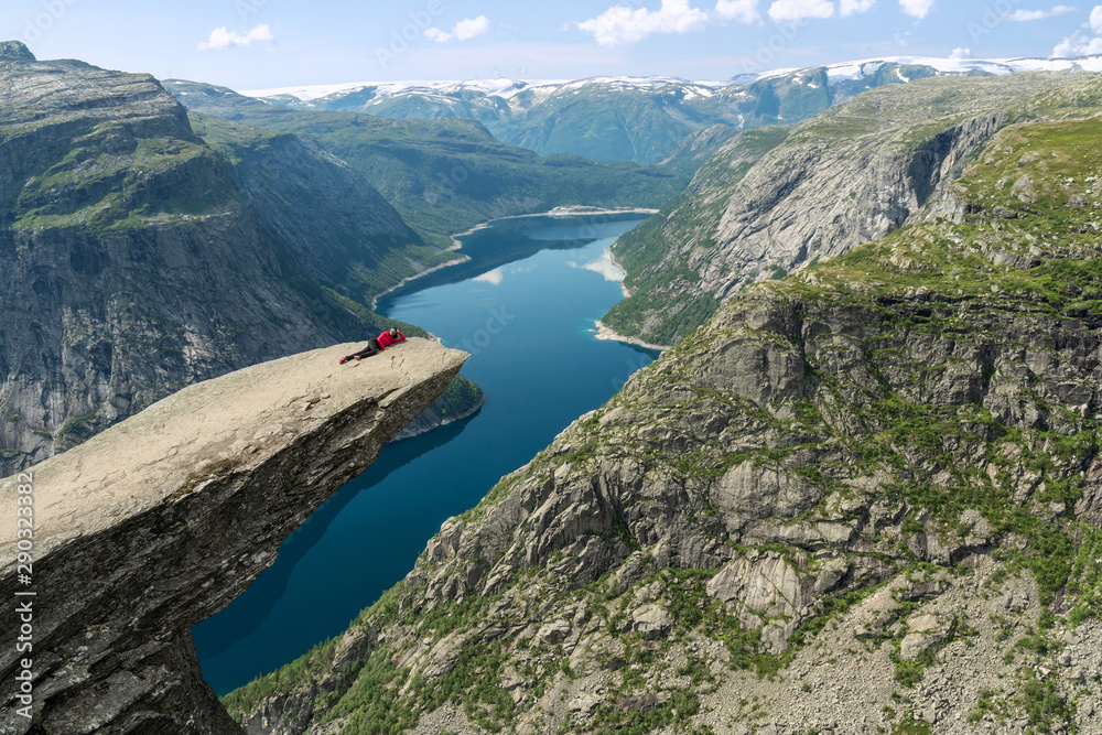 Mountain lake Ringedalsvatnet landscape, Norway. Girl laying on Trolltunga rock.