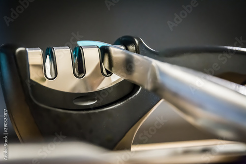 Close-up and detail of a knife in a knife sharpener kitchen tool. Metal and chrome.  photo