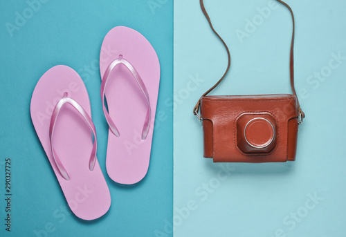 Flip flops and retro camera on blue paper background. Trip, vacation concept. Summer fashion, holiday. Beach accessories.