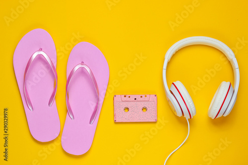 Flip flop with headphones and audio cassette on yellow background. Summertime relax. Summer vacation. Beauty and fashion. Top view. Flat lay