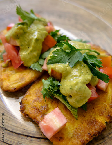 fried banana accompanied by guacamole, vegetables and meat