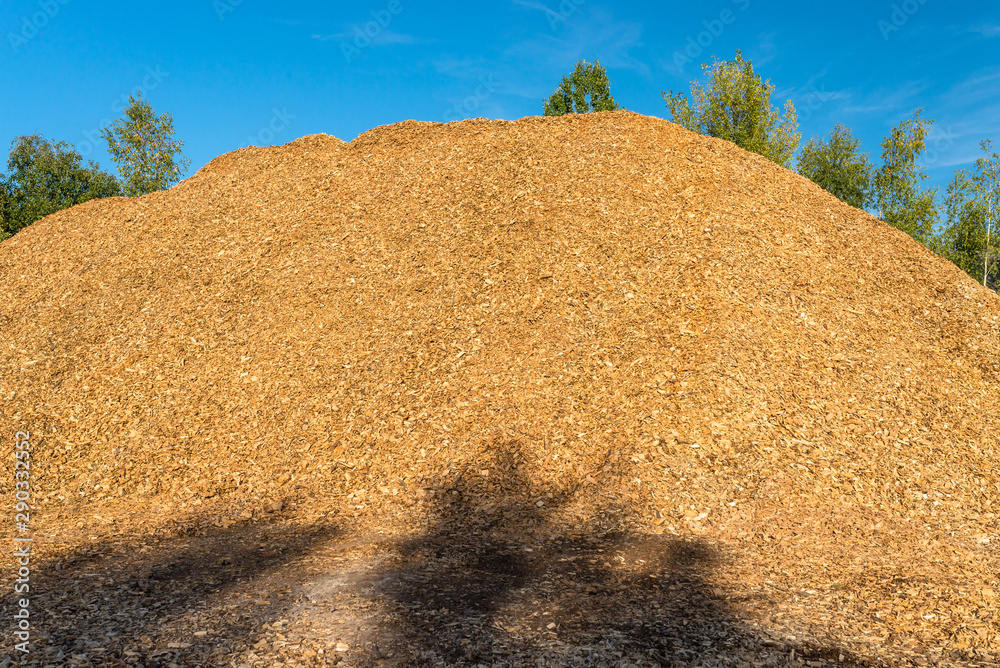 A large pile of wood chips lying on a square, with a blue sky in the background.