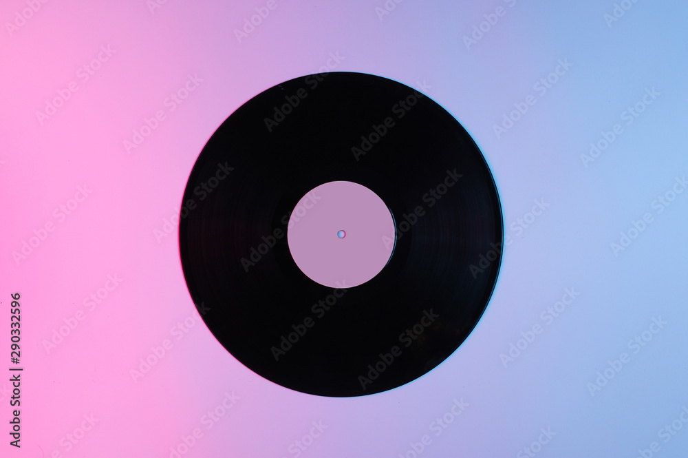 Retro style music concept. Vinyl record with gradient pink-blue neon light. Pop culture. 70s. Top view Retro style music concept. Vinyl record with gradient pink-blue neon light. Pop culture. 70s. Top view