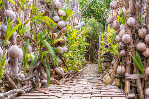A wall of old coconuts and a wooden bridge on a tropical beach in island Koh Phangan, Thailand. Travel concept