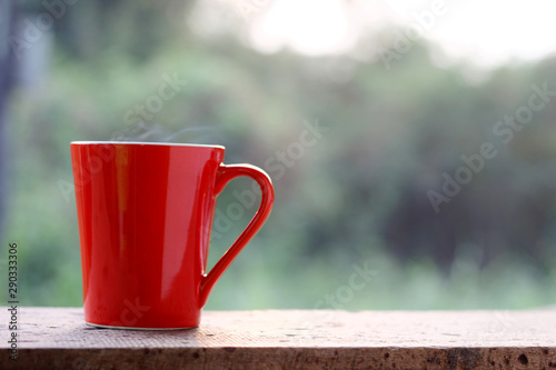 red coffee cup on wood table with sunlight