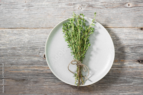 Sprigs of fresh thyme tied in a bouquet lie on a gray ceramic plate. Top view
