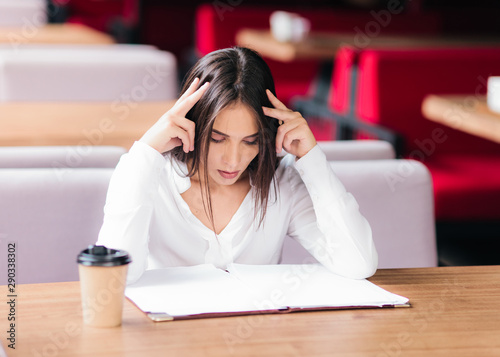 Young attractive business woman sitting at table in a cafe