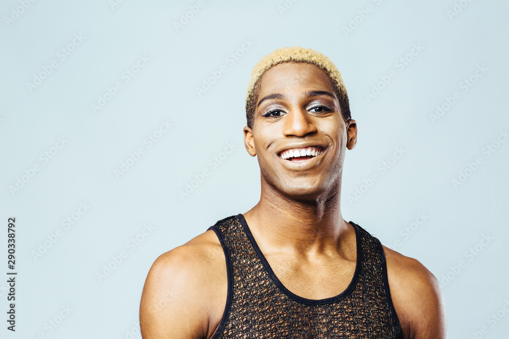 Portrait of a smiling young man with bleached hair in studio - obrazy, fototapety, plakaty 
