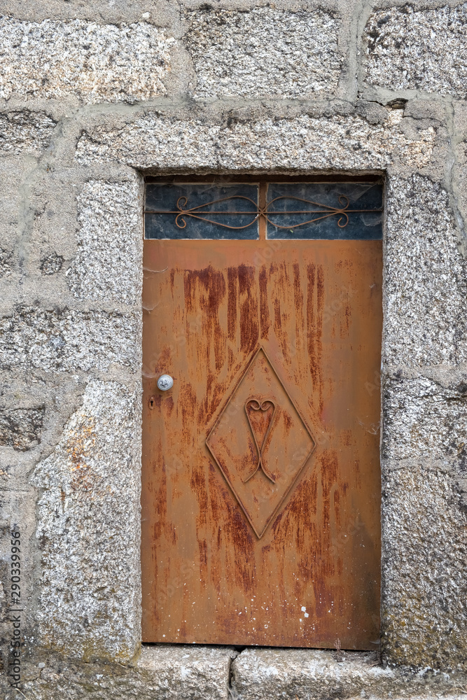 Vieja puerta de hierro pintada de marrón en casa de muros de piedra. Montalegre, Norte de Portugal.