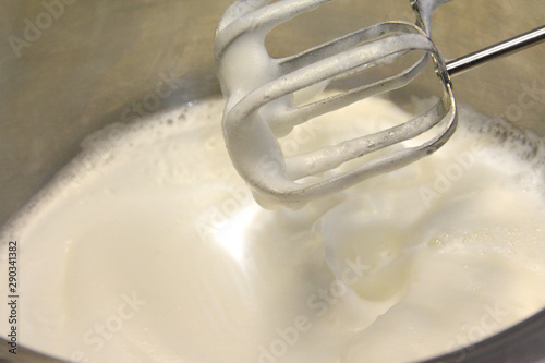 Whipped egg whites and sugar in stainless steel pot for baking cream topping