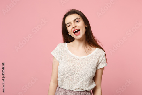 Cheerful young woman in casual light clothes posing isolated on pastel pink wall background studio portrait. People sincere emotions lifestyle concept. Mock up copy space. Blinking keeping mouth open.