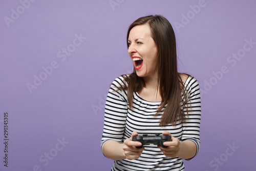 Young brunette woman girl in casual striped clothes posing isolated on violet purple background studio portrait. People sincere emotions lifestyle concept Mock up copy space Hold pc joystick play game