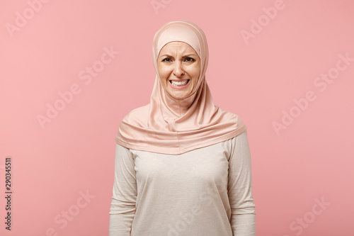 Worried displeased young arabian muslim woman in hijab light clothes posing isolated on pink background in studio. People religious Islam lifestyle concept. Mock up copy space. Crying, looking camera.