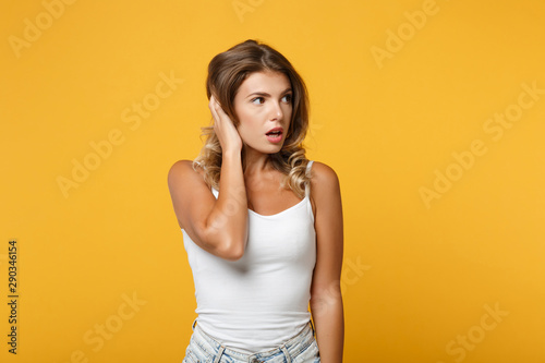 Amazed young woman in light casual clothes posing isolated on yellow orange background in studio. People sincere emotions lifestyle concept. Mock up copy space. Putting hands on head, looking aside.