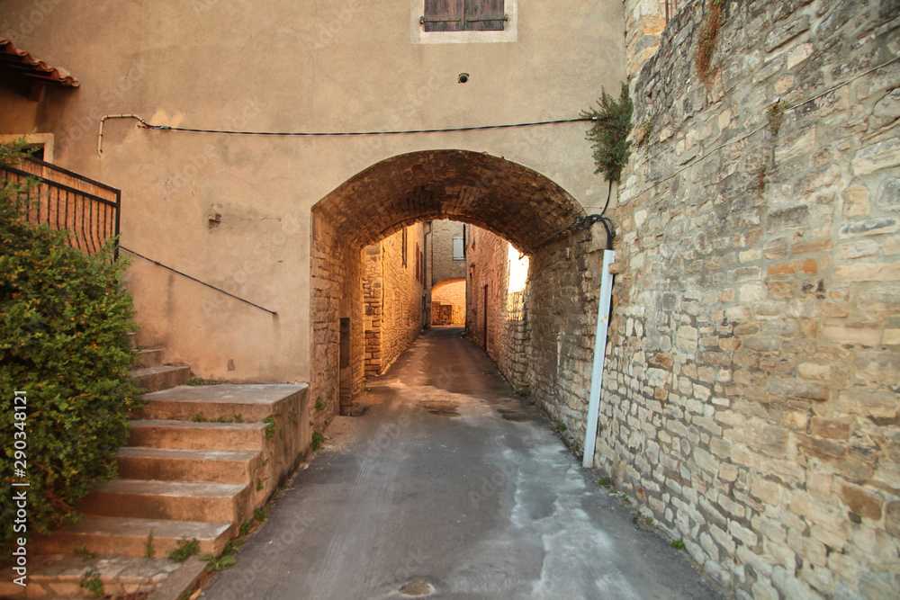 Narrow street with stone pavement of old town of Barjac. European old town at sunset, south France