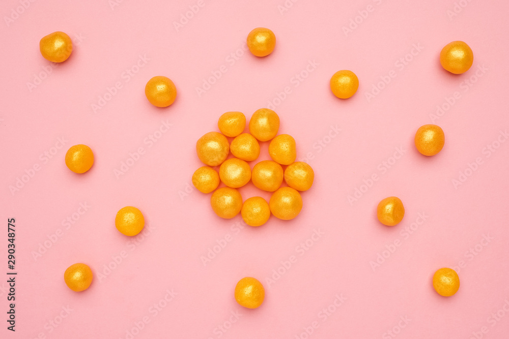 Sweet yellow candies on a pink background, round sweet food