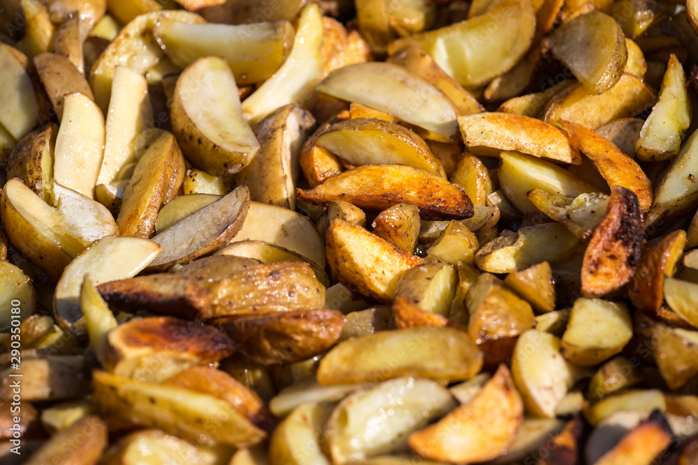 Roast potatoes in a large pan. Delicious food at the festival. Many potatoes on the table in a metal tray. Roast potatoes in a large pan. Delicious food at the festival. Many potatoes on the table in a metal tray.