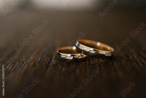elegant wedding engagement rings in white and yellow gold on brown chocolate wooden background, close-up, copy space
