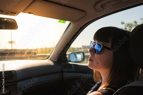 A young and attractive girl with piercings travels by car with sunglasses.