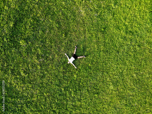 View from above happy man lying on fresh green grass relaxing