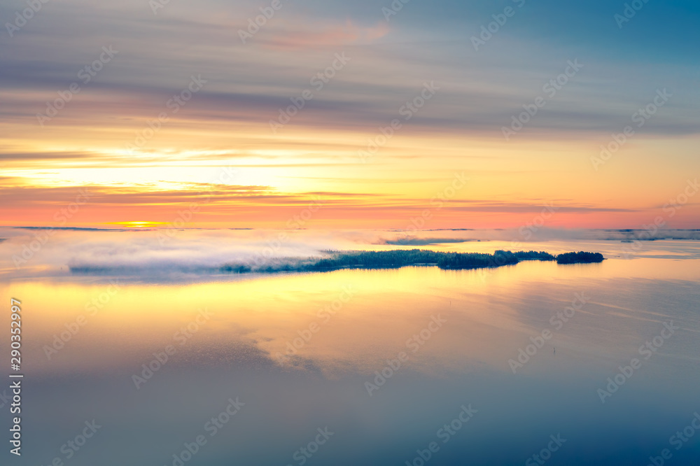 Long Exposure of Sunrise at the Paijanne lake. Beautiful scape with sunrise sky,fog, pine forest and water. Lake Paijanne, Finland.