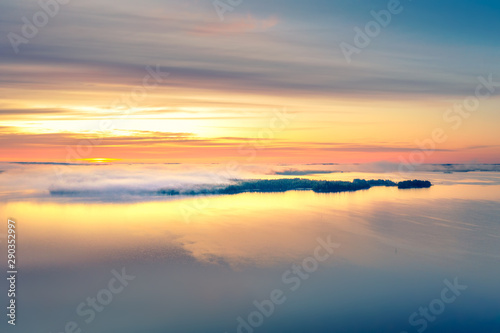 Long Exposure of Sunrise at the Paijanne lake. Beautiful scape with sunrise sky,fog, pine forest and water. Lake Paijanne, Finland. © Della_Liner