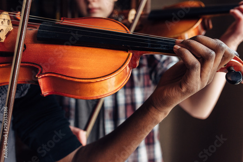 Black and Caucasian girls practicing violin
