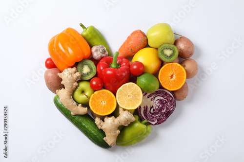 Heart laid out of vegetables and fruits on white background, copy space
