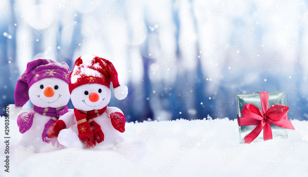 Funny two snowmen with gift box in the winter scenery. Christmas decoration
