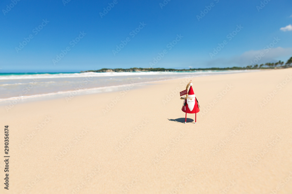 Greeting card with Santa toy on beach close to sea Greeting card with Santa toy on beach close to sea