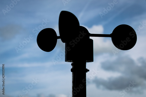 Wind speed meter or anemometer silhouetted against a partly cloudy sky photo