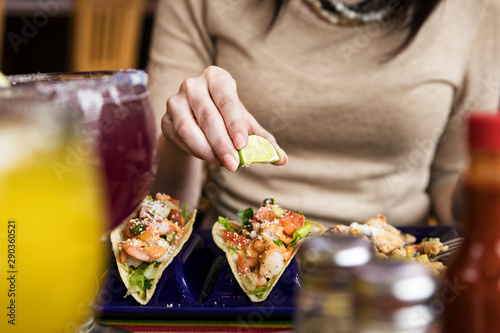 Cinco: Woman Squeezing Lime On Shrimp Tacos photo